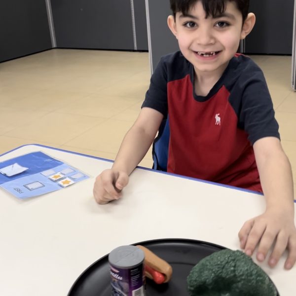 Male student smiling with plate of food in classroom