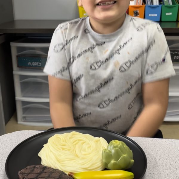 Male student smiling with plate of food in classroom