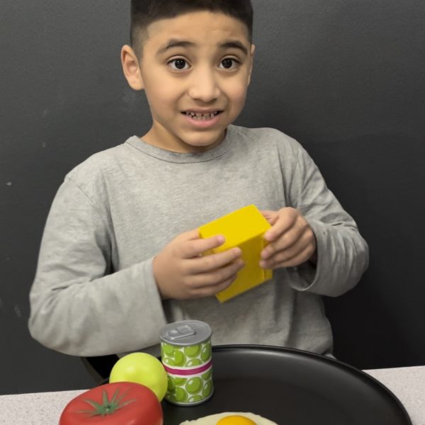 Male student smiling with plate of food in classroom
