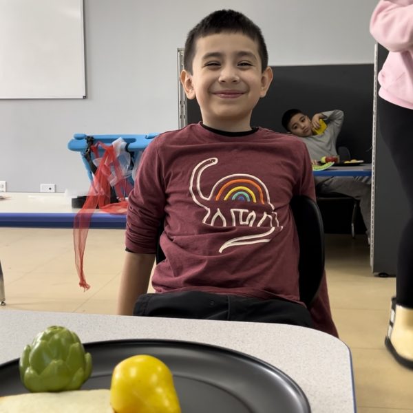 Male student smiling with plate of food in classroom