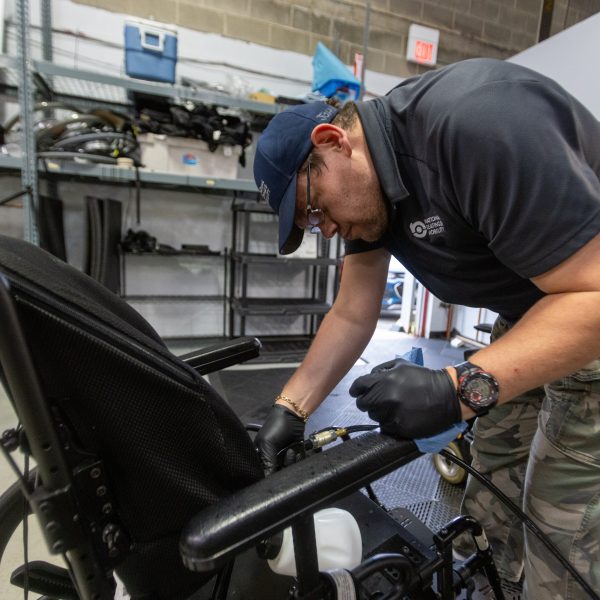 John working on wheelchair at his job at National Seating & Mobility